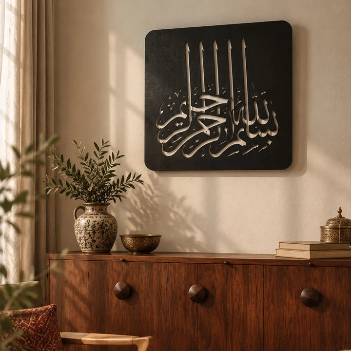 Bismillahirrahmanirrahim yazılı siyah metal Kufi hat tablosunun aydınlık bir yaşam alanında kullanımı; modern İslami ev dekorasyonu, manevi duvar sanatı ve yeni ev hediyesi arayanlar için dekoratif Besmele tasarımı.